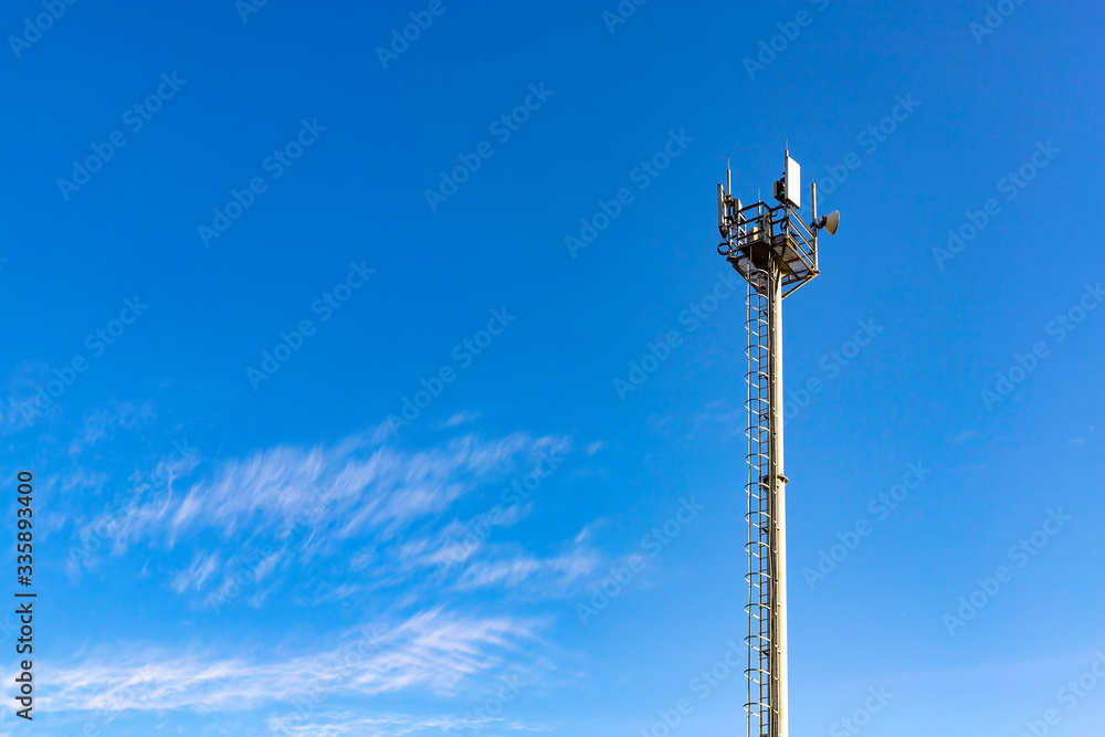 Communications tower with antennas against blue sky.