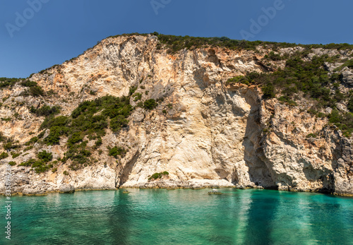 Natural cliff rocks reflected in blue water of Ionian sea in Summertime, Greece