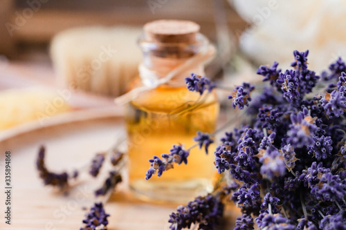 Concept of natural organic oil in cosmetology. Moisturizing skin care and aromatherapy. Gentle body treatment. Atmosphere of harmony relax. Wooden background, lavender flower, brush, soap. Close up 