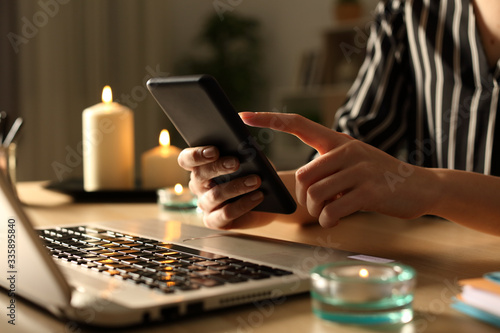 Girl hands using phone on power outage with candles