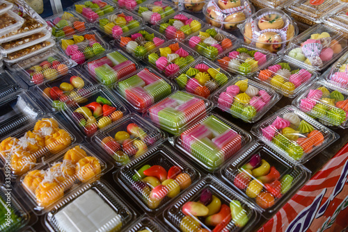 Plastic containers containing Luk Chub, a traditional Thai multi-coloured sweet dessert made from ground mung beans, coloured and hand shaped, at a market stall, Thailand