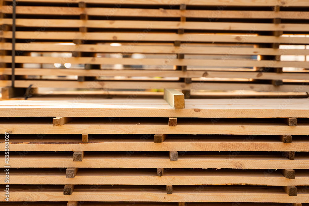 Warehouse for sawing boards on a sawmill outdoors. Timber mill, sawmill. Storage of planed wooden boards. Piles of wooden boards in the sawmill. Planking. Industry. Warehouse for sawing boards on a sawmill outdoors. Timber mill, sawmill. Storage of planed wooden boards. Piles of wooden boards in the sawmill. Planking. Industry.