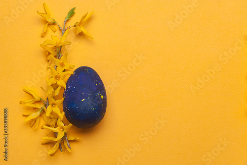 Photography Blue easter egg with yellow flowers on a yellow background