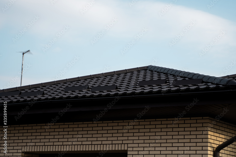 Brown metal tile roof. Roof metal sheets. Modern types of roofing materials. Roof of the house, metal roof tile against the blue sky. Building. Brown metal tile roof. Roof metal sheets. Modern types of roofing materials. Roof of the house, metal roof tile against the blue sky. Building.