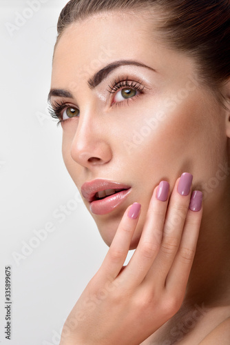 Beautiful Young Woman with Clean Fresh Skin. Close up Portrait.  Fashion Model Girl Face. Perfect Skin. Professional Makeup. Fashion shiny highlighter on skin  sexy gloss lips. Perfect manicure.