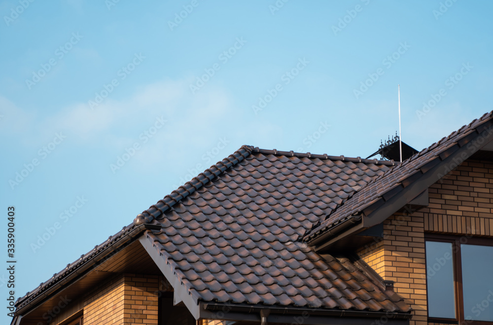 Brown natural tile roof. Modern types of roofing materials. Roof of the house, Natural roof tile against the blue sky. Building.