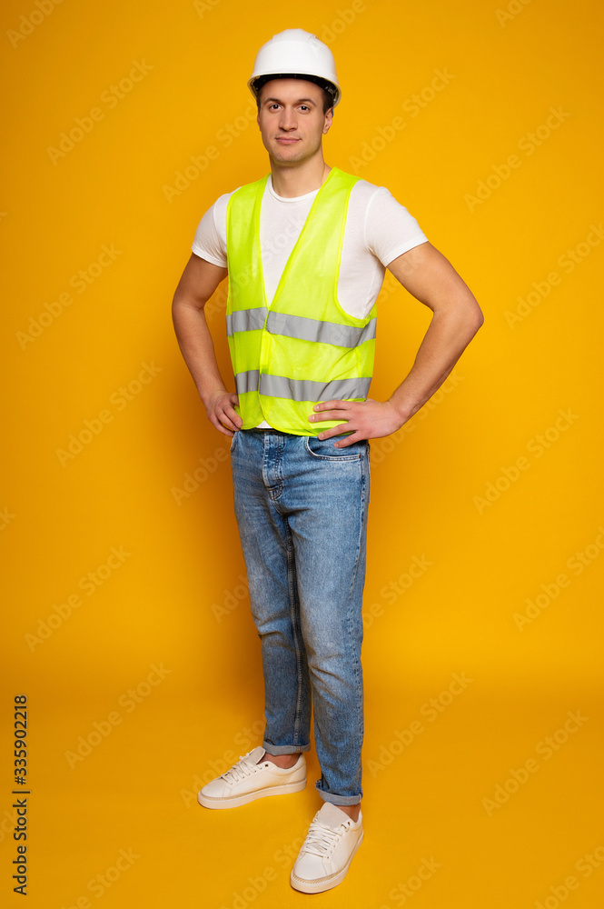 Close up photo of young happy and confident foreman or architect in build helmet is posing isolated on yellow background. Close up photo of young happy and confident foreman or architect in build helmet is posing isolated on yellow background.