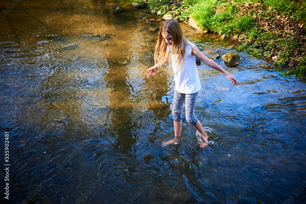 Child cute blond girl playing in the creek. Girl walking barefoot in ...