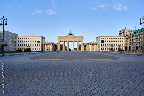 view on the famous Brandenburg gate on the Pariser square in Berlin city, parisian square without tourists and visitors - deserted, blue sky, small clouds