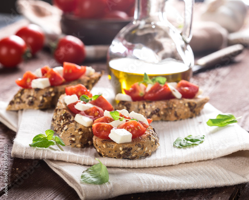 Bruschetta with tomatoes, mozzarella cheese and basil on wooden background.