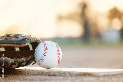 Fototapeta Naklejka Na Ścianę i Meble -  Baseball glove and ball on park sport field at sunset close up, copy space on blurred background.