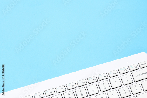 Close up white computer keyboard on blue background. View from above.