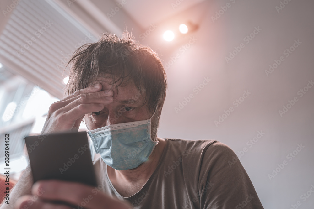 Worried man using mobile phone in home quarantine self-isolation Worried man using mobile phone in home quarantine self-isolation