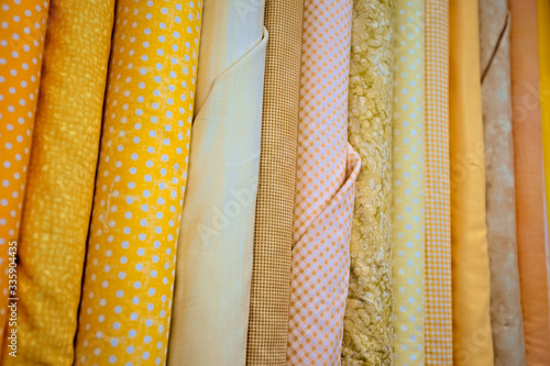 Bright colorful yellow material cloth Amish country store Ohio. Cotton reams on shelf for sale and display. Bright and fun colors. Sewing for clothes and household furnishing. Despain Rekindle Photo.