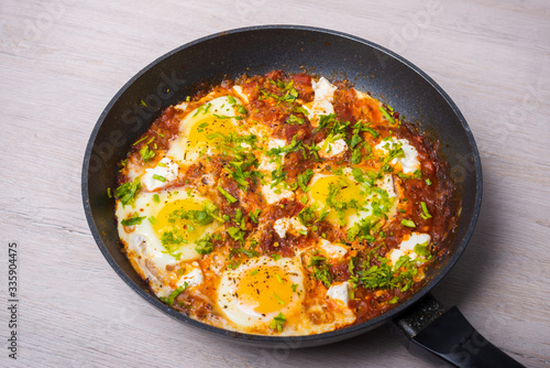 Freshly cooked shakshuka in a pan on wooden background