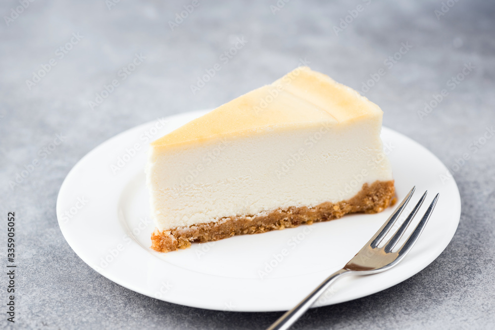 Slice of plain cheesecake on white plate. Dessert cake made with cream cheese. Isolated on grey concrete background Slice of plain cheesecake on white plate. Dessert cake made with cream cheese. Isolated on grey concrete background