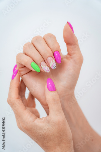 Lots of color gloss manicure hands has different blotches in pink background.