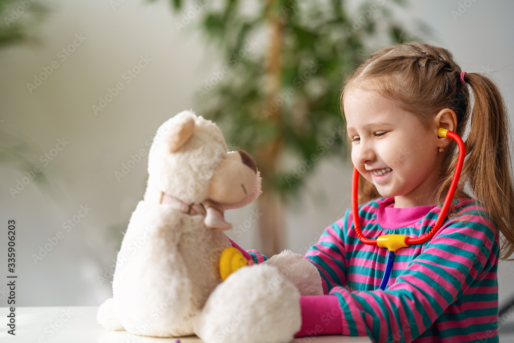 Smiling small girl wearing in everyday clothes, using stethoscope on teddy bear. Smiling small girl wearing in everyday clothes, using stethoscope on teddy bear.