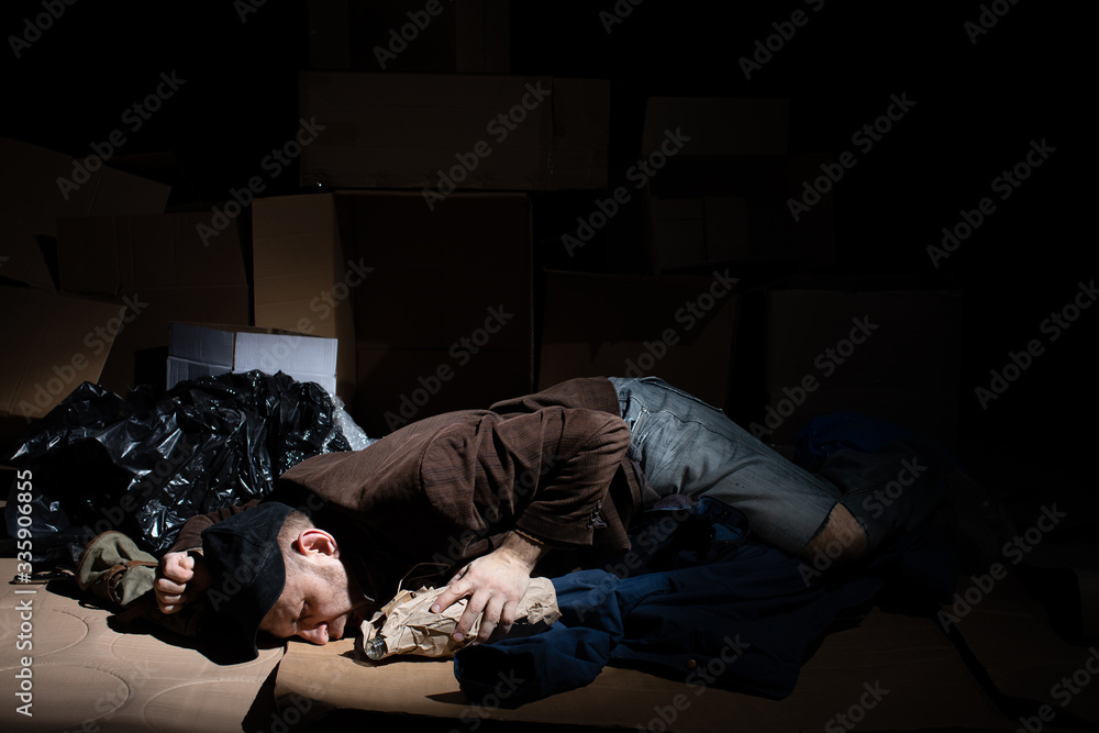 A homeless middle-aged man sleeps in cardboard boxes outside. A homeless middle-aged man sleeps in cardboard boxes outside.