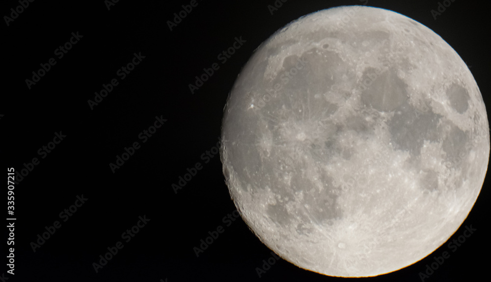 Full moon on the black background seen through telescope with blank space on the left.12.09.2019. Full moon on the black background seen through telescope with blank space on the left.12.09.2019.