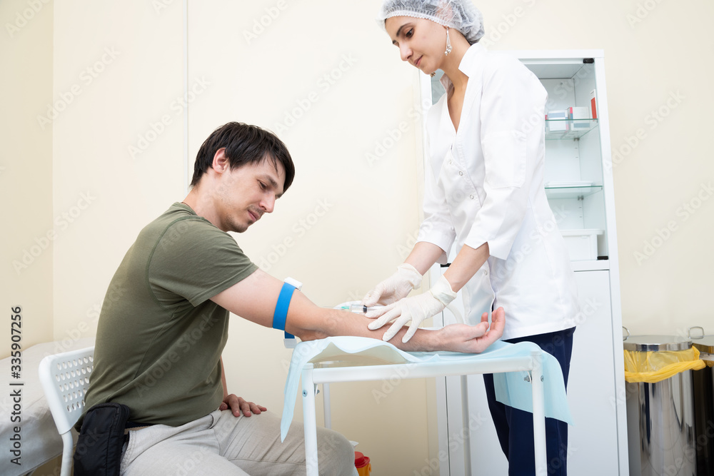 Obraz premium the nurse is going to loosening a tourniquet during the injection. intravenous injection it may be contrast administration for MRI or drugs or a fence of tests for diseases. coronavirus covid 19