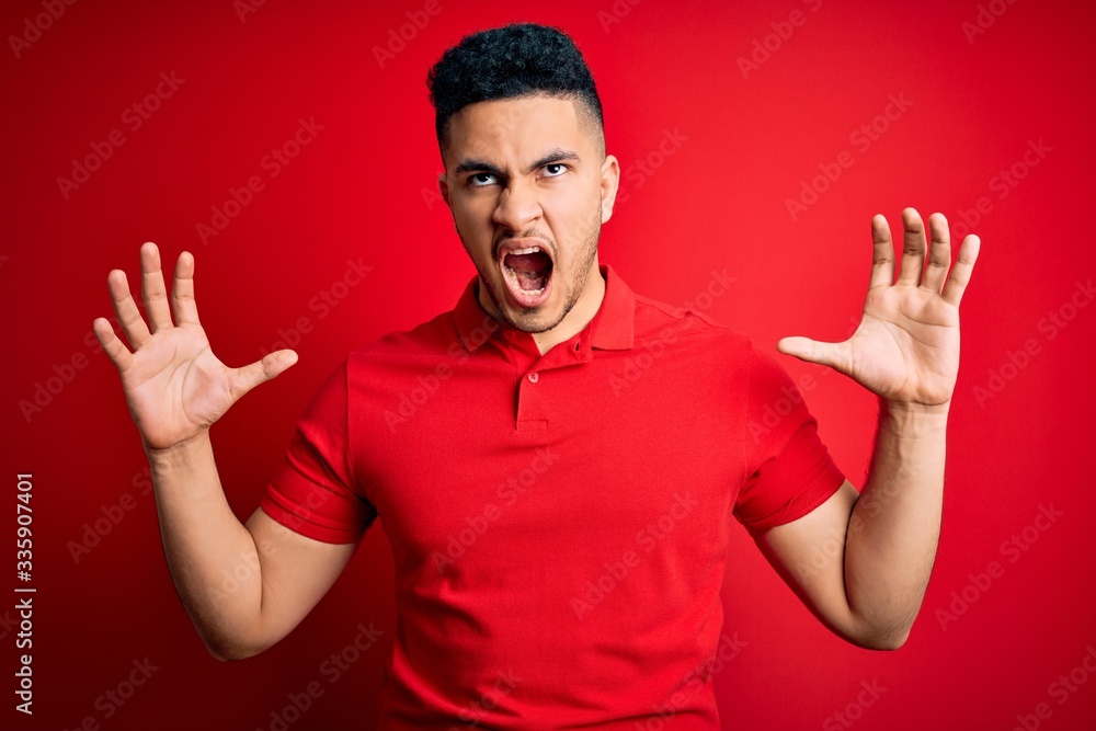 Young handsome man wearing red casual polo standing over isolated background crazy and mad shouting and yelling with aggressive expression and arms raised. Frustration concept. Young handsome man wearing red casual polo standing over isolated background crazy and mad shouting and yelling with aggressive expression and arms raised. Frustration concept.