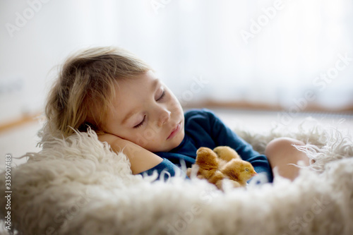 Cute blond toddler boy, sleeping with newborn chicks