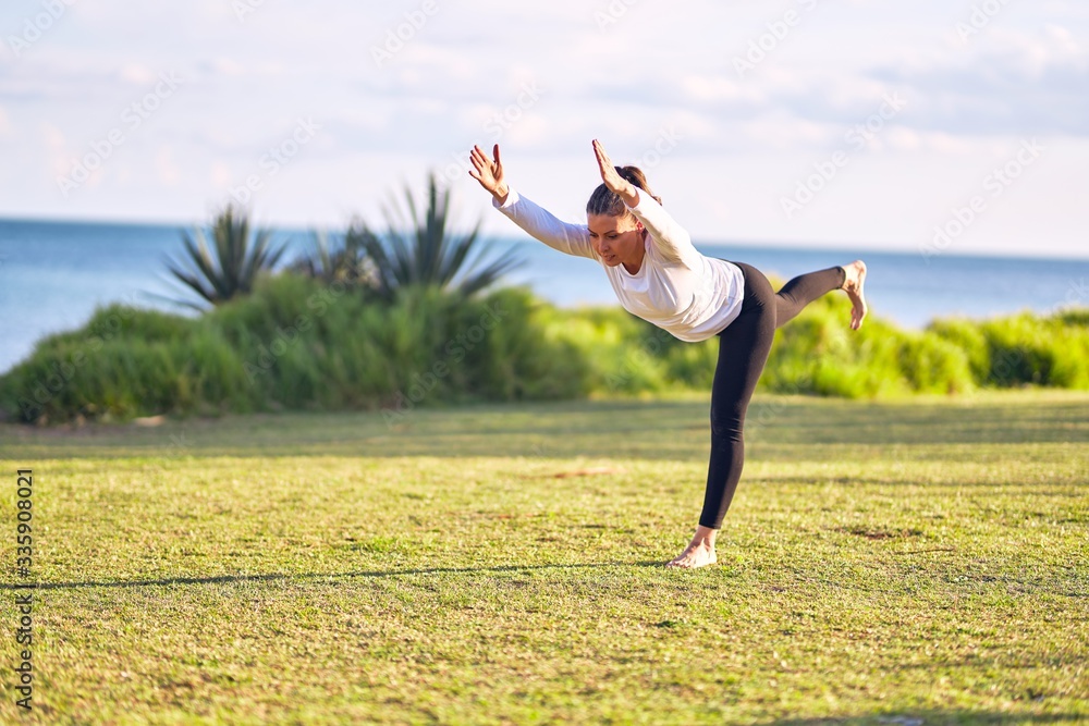Young beautiful sportwoman practicing yoga. Coach teaching warrior pose at park Young beautiful sportwoman practicing yoga. Coach teaching warrior pose at park