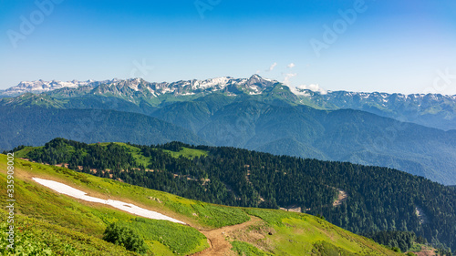 View over the Green Valley, surrounded by high mountains with snow on a clear summer day.