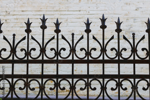 wrought iron fence carved on the background of a brick wall