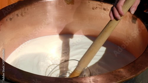 Milch im Kupferkessel rühren um Käse herzustellen photo