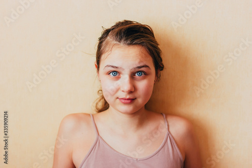 a natural girl with blue eyes without retouching is surprised and interested. Caucasian teenager in home simple atmosphere looking at the camera on yellow background. Natural beauty and .purity photo