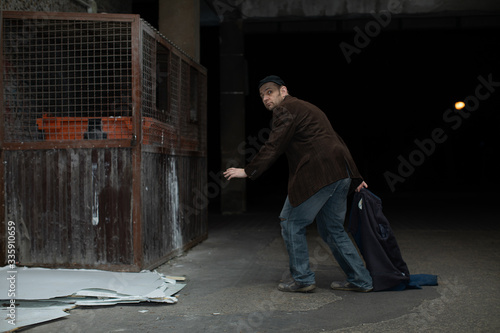 A middle-aged homeless man has found garbage cans and is heading towards him.