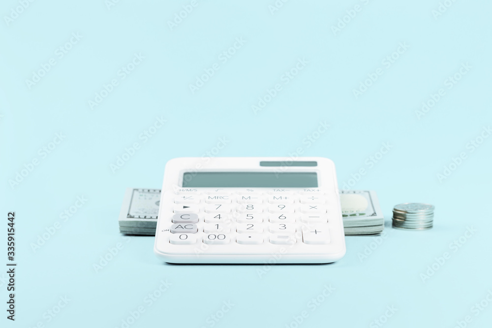 Finance concept with calculator and stack of money dollars on blue. Finance markets investments loans earnings concept. Personal accounting debts and credits with copy space Finance concept with calculator and stack of money dollars on blue. Finance markets investments loans earnings concept. Personal accounting debts and credits with copy space