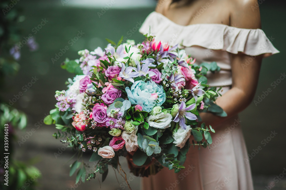 Bride holding in hands amazing huge blooming bouquet on wedding ceremony. Pink roses, peony, red tulips and greens close up. Bride holding in hands amazing huge blooming bouquet on wedding ceremony. Pink roses, peony, red tulips and greens close up.