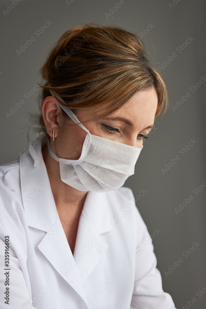 Doctor with face covered with mask. Portrait of young woman wearing the uniform and mask to avoid virus infection and to prevent the spread of disease. Real people, authentic situations Doctor with face covered with mask. Portrait of young woman wearing the uniform and mask to avoid virus infection and to prevent the spread of disease. Real people, authentic situations