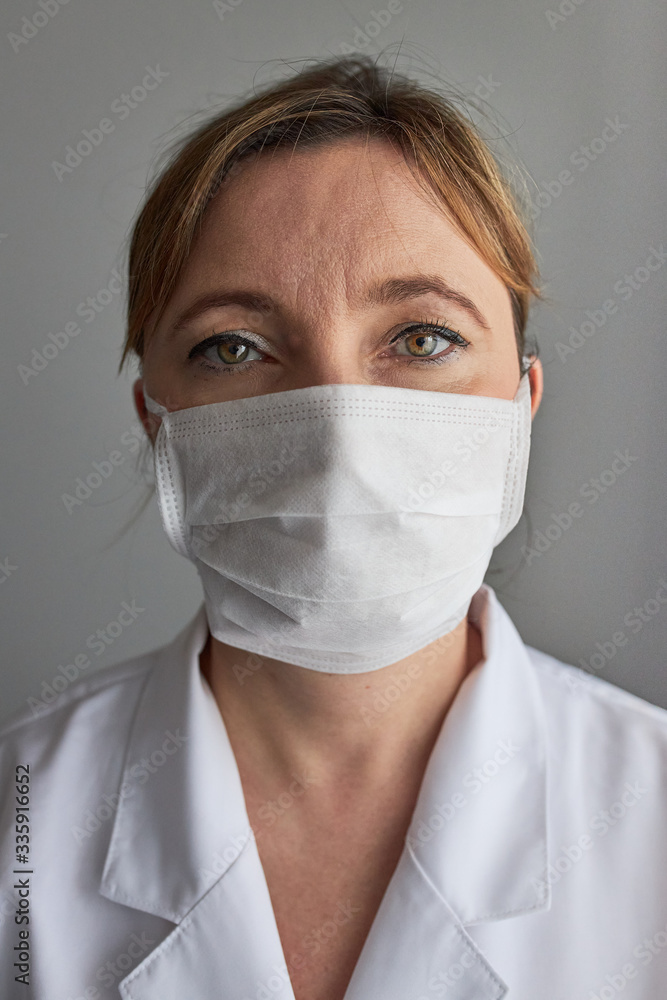 Doctor with face covered with mask. Portrait of young woman wearing the uniform and mask to avoid virus infection and to prevent the spread of disease. Real people, authentic situations Doctor with face covered with mask. Portrait of young woman wearing the uniform and mask to avoid virus infection and to prevent the spread of disease. Real people, authentic situations