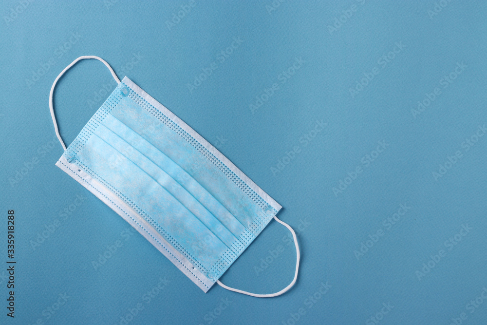 Protective blue medical face mask on blue background, Prevention of virus, Space for text Protective blue medical face mask on blue background, Prevention of virus, Space for text