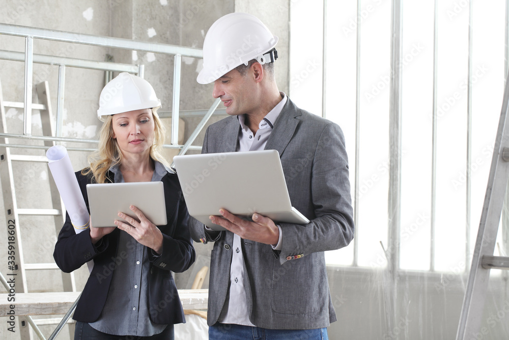 man and woman architects or engineers with computer work together in the inside the construction building site
