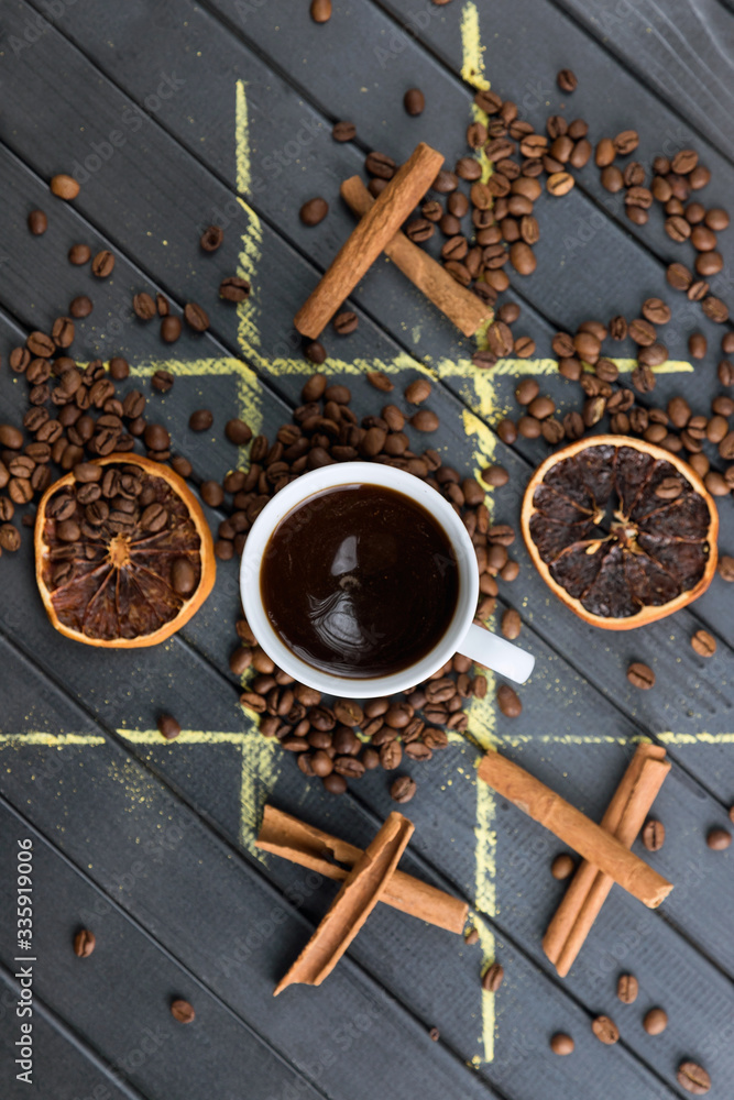 still life on a black wooden table. TIC-TAC-toe game with food. coffee beans and cinnamon on the table. white coffee Cup. still life on a black wooden table. TIC-TAC-toe game with food. coffee beans and cinnamon on the table. white coffee Cup.