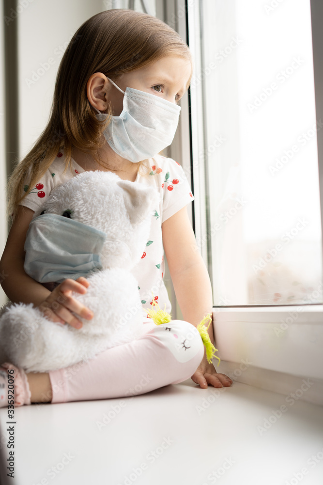 Sad child and his teddy bear both in protective medical masks. Children and illness COVID-2019 disease concept Sad child and his teddy bear both in protective medical masks. Children and illness COVID-2019 disease concept