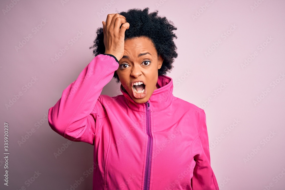 Young African American afro sportswoman with curly hair wearing sportswear doin sport surprised with hand on head for mistake, remember error. Forgot, bad memory concept. Young African American afro sportswoman with curly hair wearing sportswear doin sport surprised with hand on head for mistake, remember error. Forgot, bad memory concept.