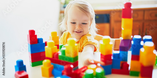 Little girl playing with colorful plastic construction blocks