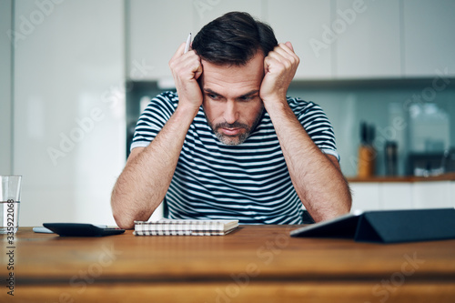 Depressed man holding head while stressing over money and home finances