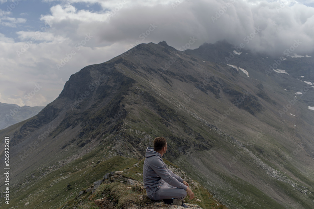 Young man meditates on the top of Alpine mountains.