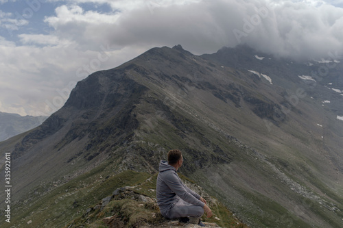 Young man meditates on the top of Alpine mountains. © fotoplaton