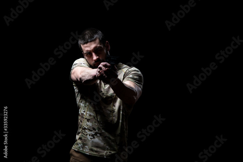 Fototapeta Naklejka Na Ścianę i Meble -  Military Man Holding Gun Isolated on Black Background