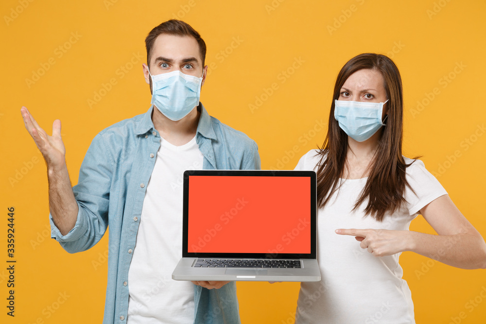 Two people in sterile face masks using laptop pc isolated on yellow background studio. Epidemic pandemic rapidly spreading coronavirus 2019-ncov medicine flu virus ill sick disease treatment concept. Two people in sterile face masks using laptop pc isolated on yellow background studio. Epidemic pandemic rapidly spreading coronavirus 2019-ncov medicine flu virus ill sick disease treatment concept.