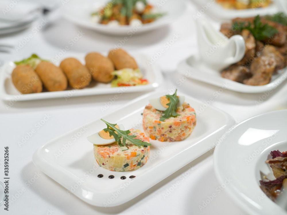 Olivier salad on a plate on a white tablecloth