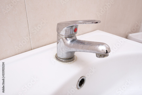 Fotografija Dirty faucet with limescale, calcified water tap with lime scale on washbowl in